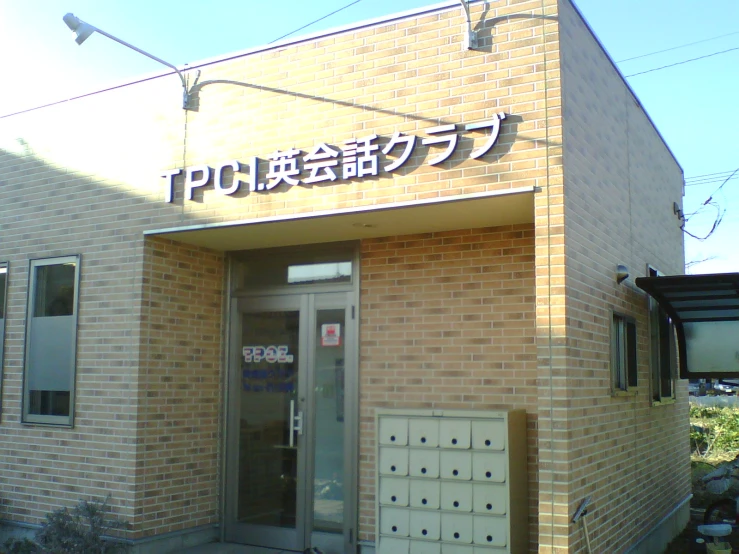 a tan brick building with a foreign sign on the front door