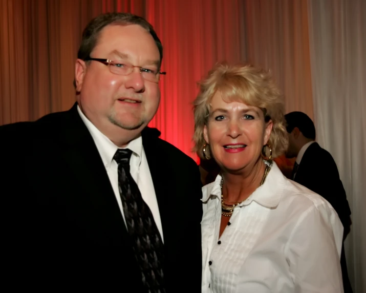 a man in glasses standing next to a woman