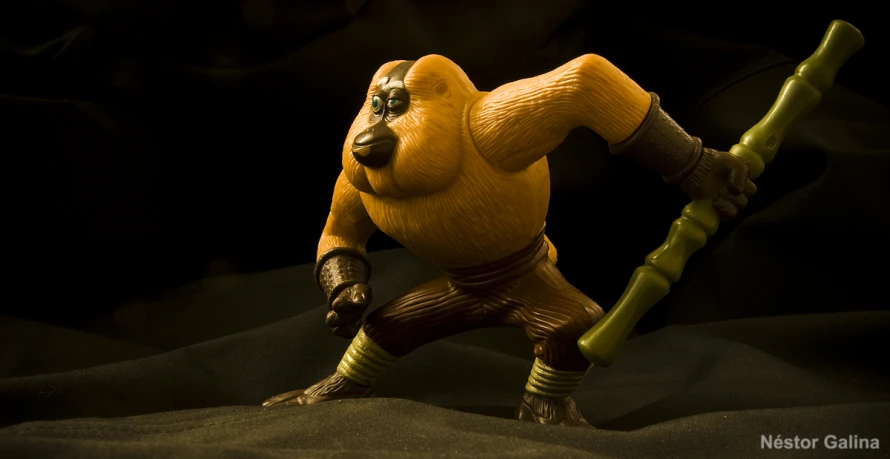 a monkey figure holding a wooden stick in his hands