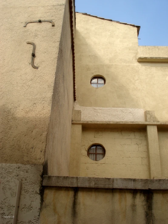 two round windows in a stucco building