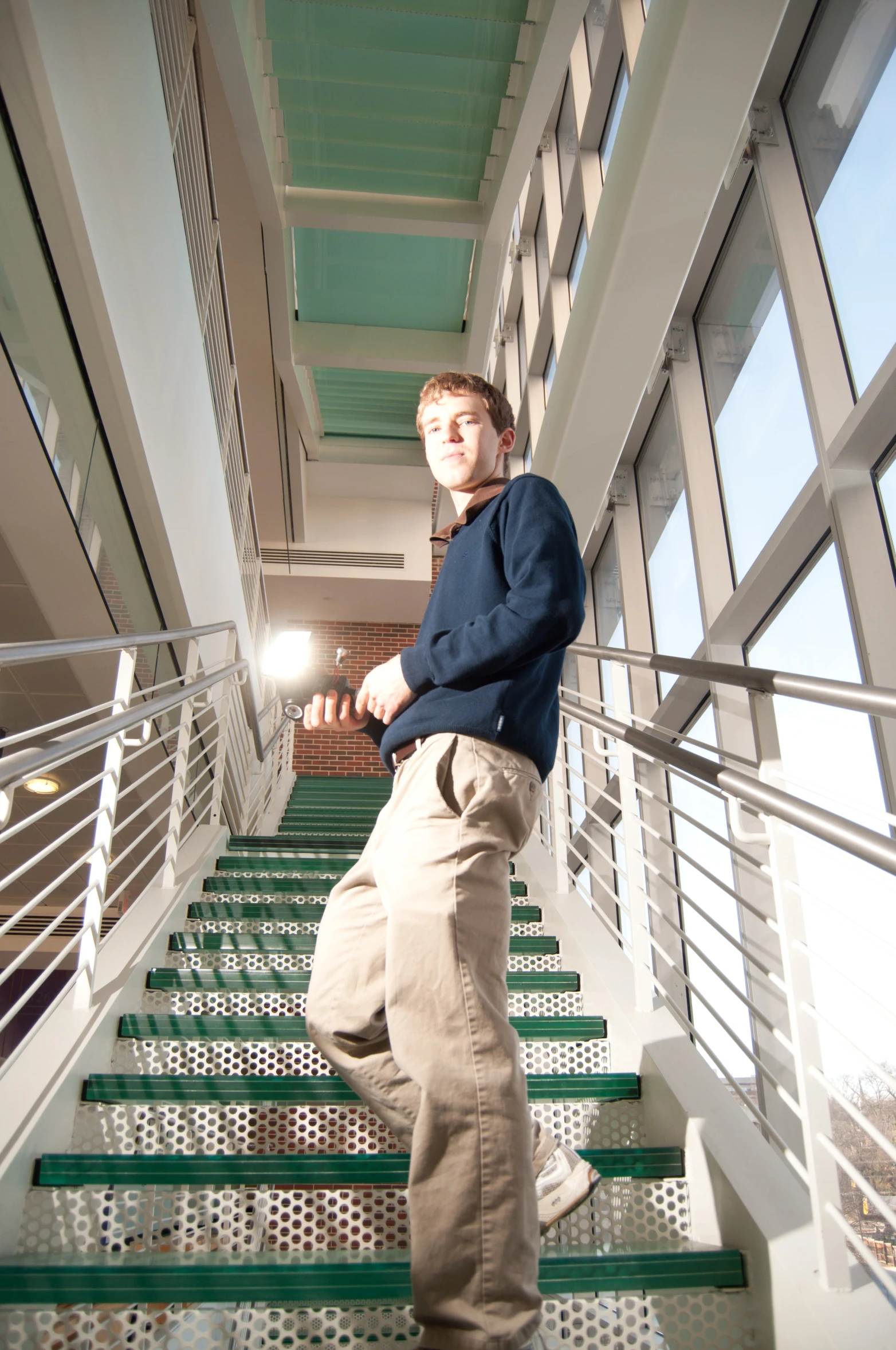 man in sweater standing on metal hand rail with stairs