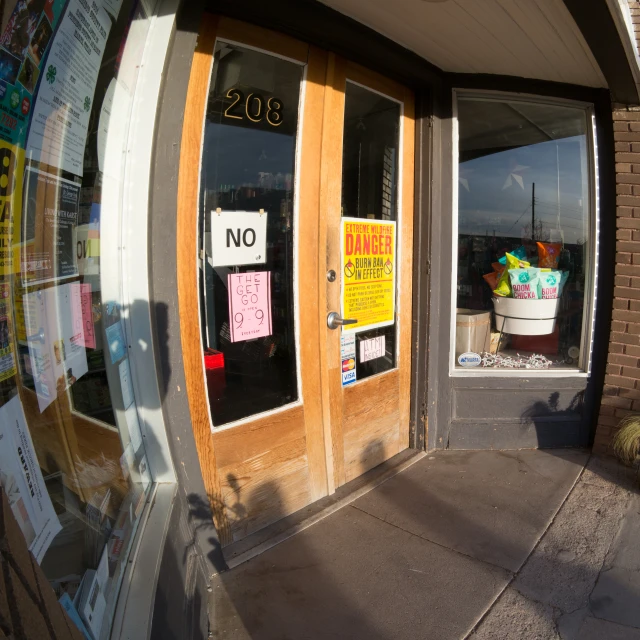 a glass door with signs about a no parking area and a flower pot outside