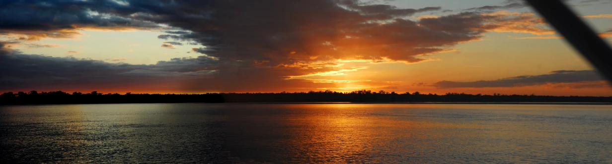 sun behind clouds with reflections on water