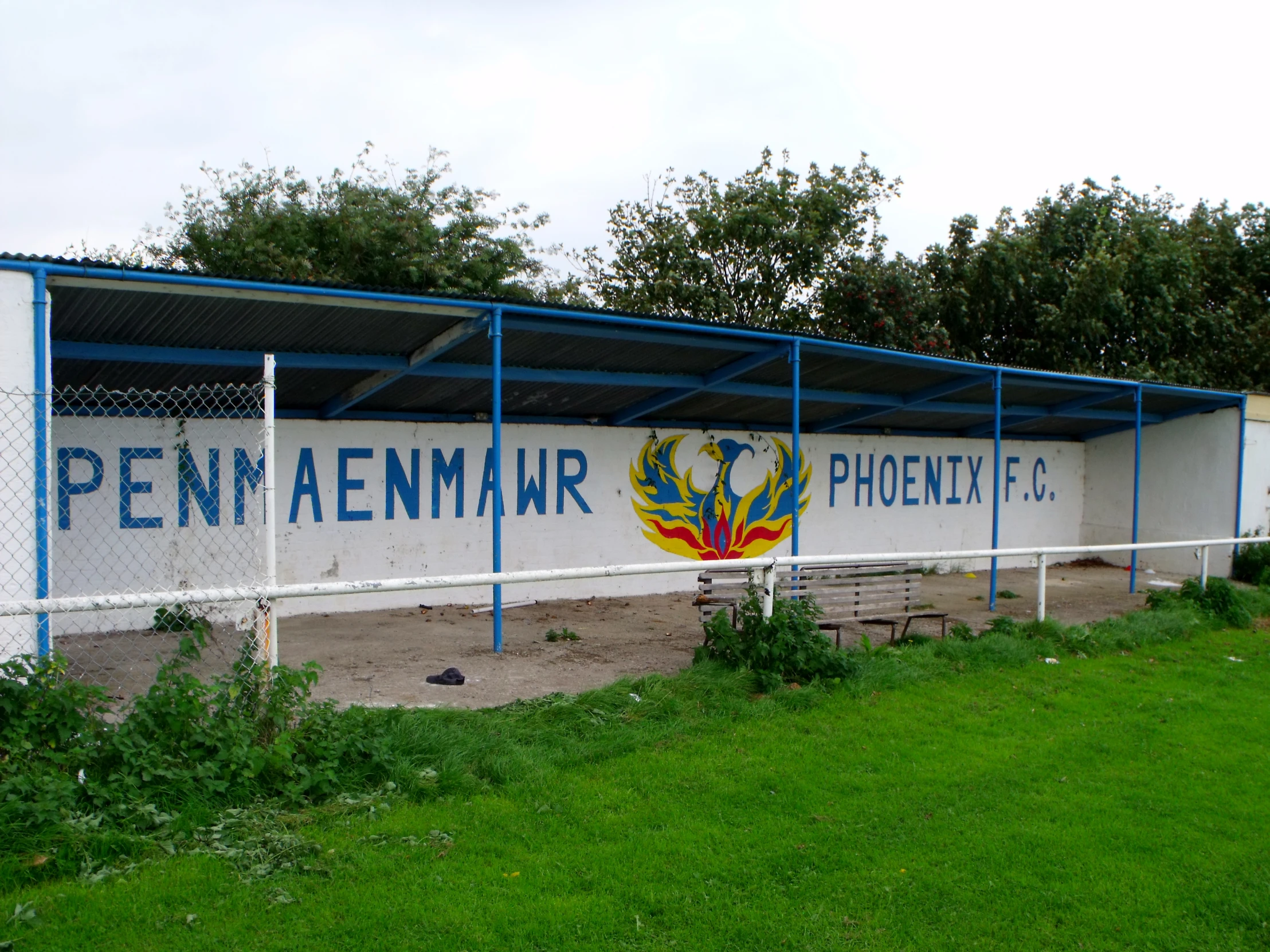 the soccer goal stands next to a white fence and blue pillars