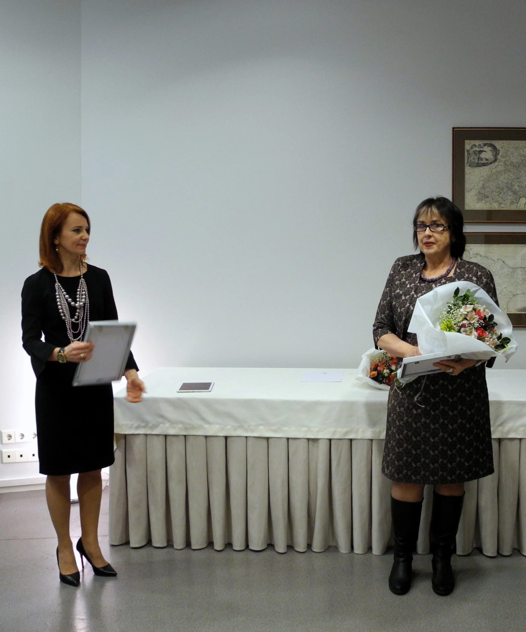 two women are standing in front of a white table