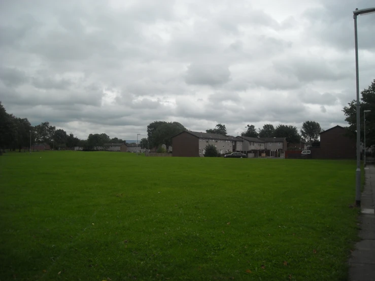 a grassy field with houses in the distance