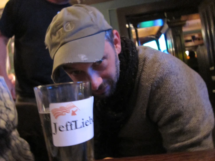 man in hat with a half empty glass and red and white sticker