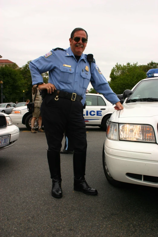 a man dressed in police uniform standing in front of some other vehicles