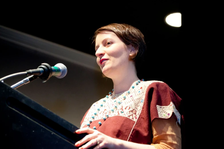 a woman is standing at a podium while looking off into the distance