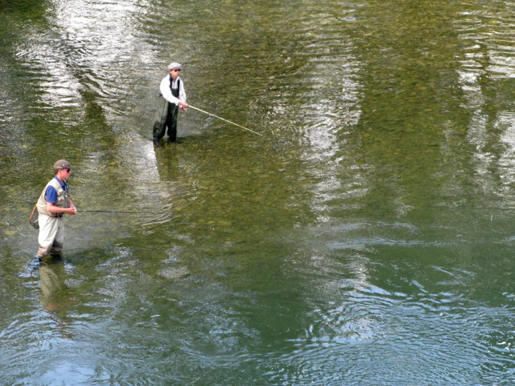 two men standing in the water holding a stick