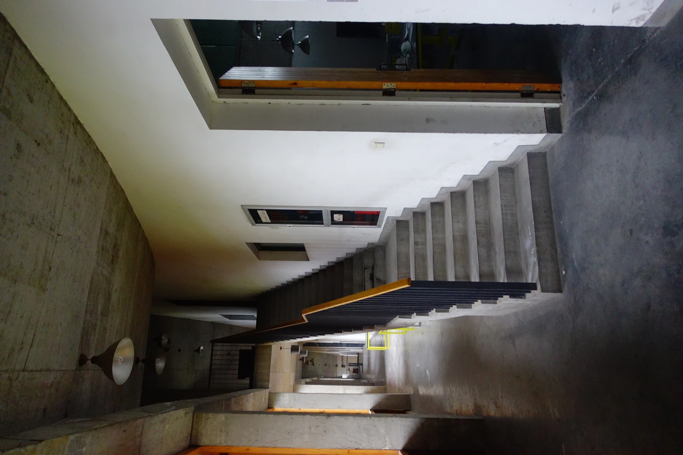 an empty hallway with several stairs and lights hanging from the ceiling