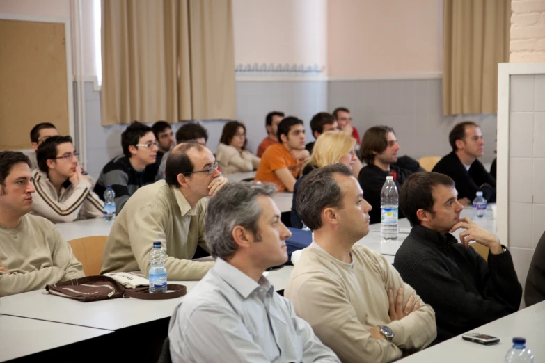 there are many men sitting at tables in a conference hall