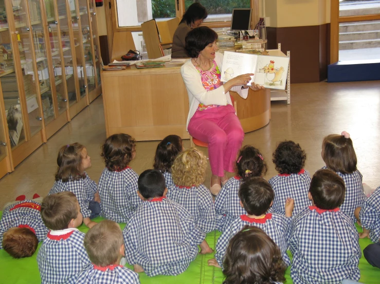 children in school uniforms reading books to children