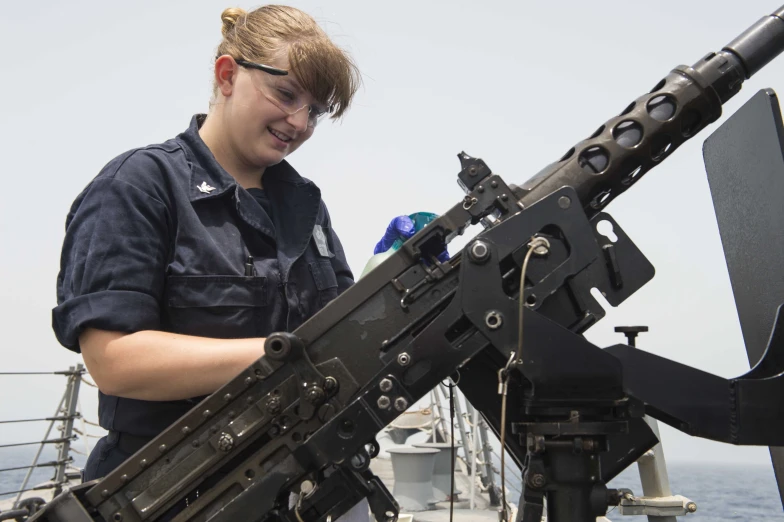 a woman holding a machine gun while standing on a ship