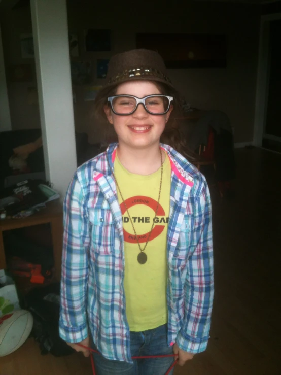 a boy in a plaid shirt and hat wearing glasses and a big necklace