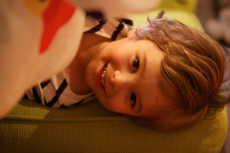 a little girl with blond hair smiles as she lays on a bed