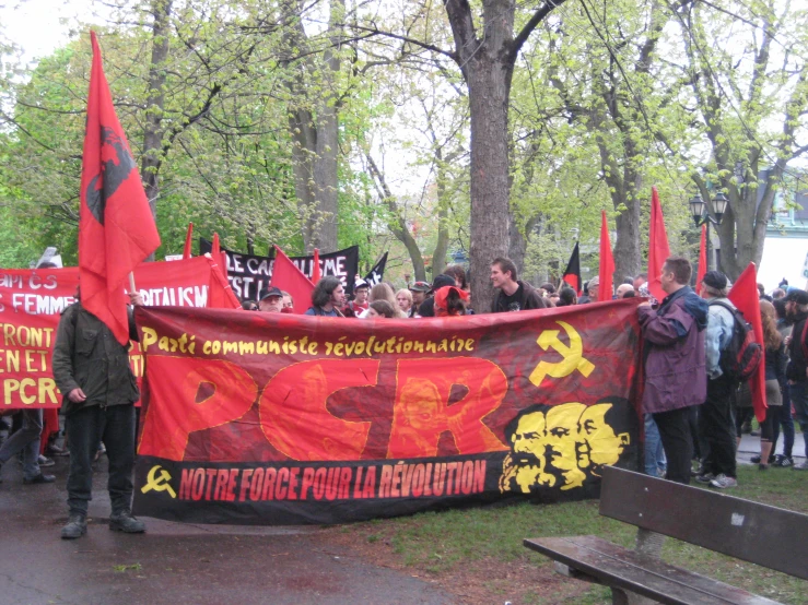 a crowd of people carrying protest signs in a park