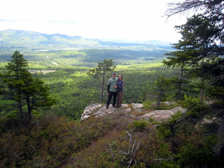 two people pose for the camera while standing on a rocky outcropping