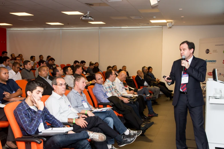 an audience in chairs watching a speaker giving a lecture