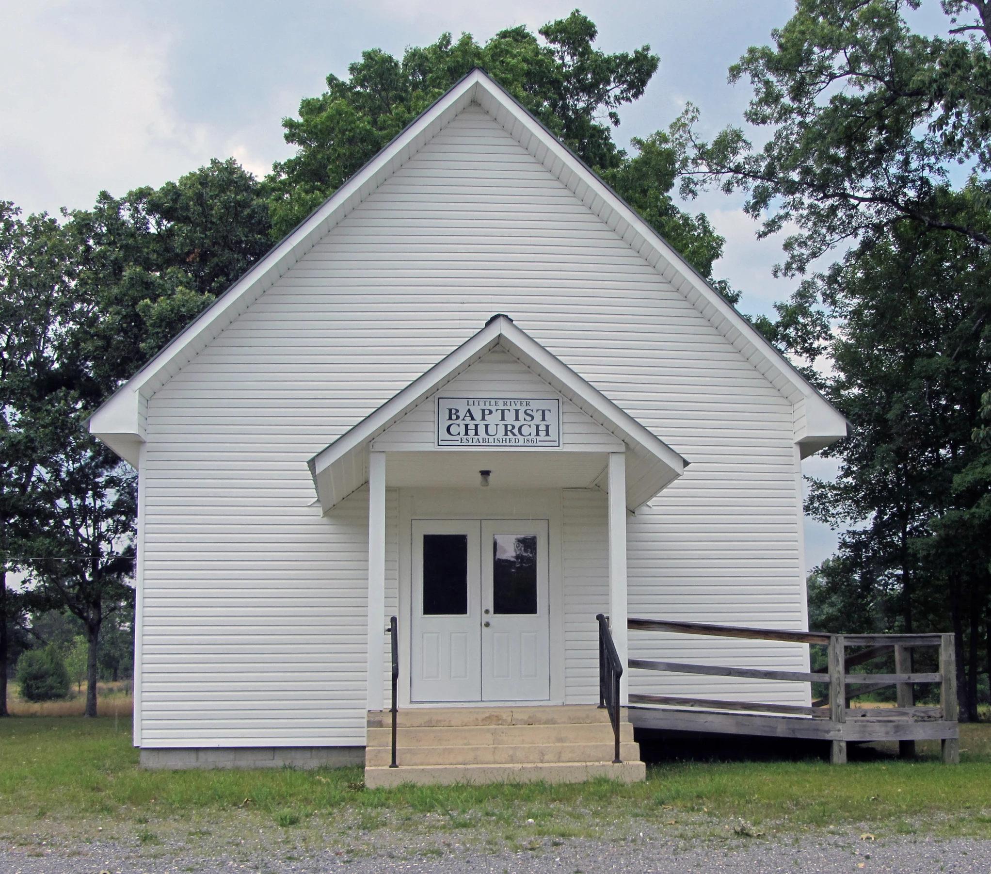 a white building with a porch and fence