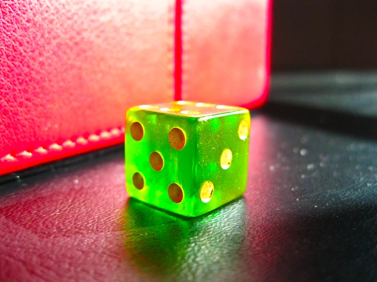 a green dice sitting on top of a red case
