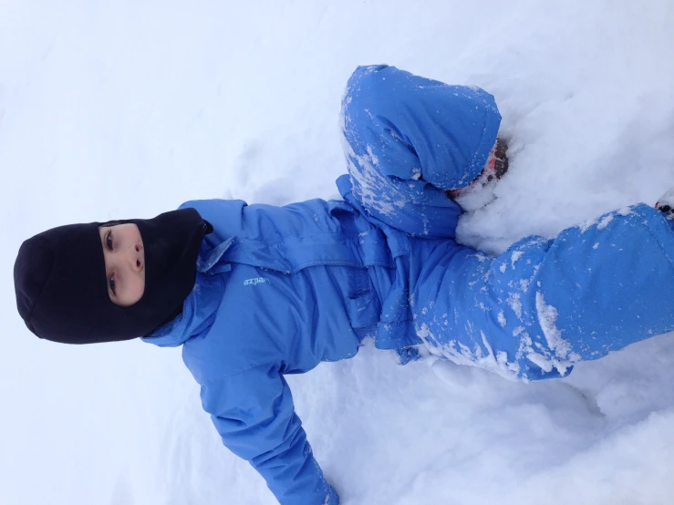 a little  sitting in the snow wearing a jacket