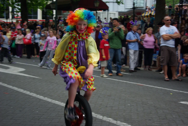 a small child in clown suit riding a toy bicycle