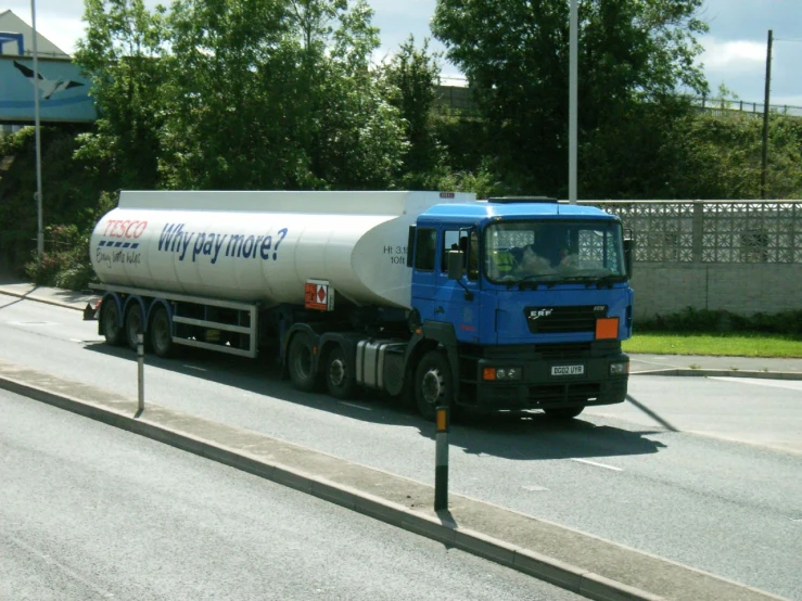 a truck driving down a road next to some trees