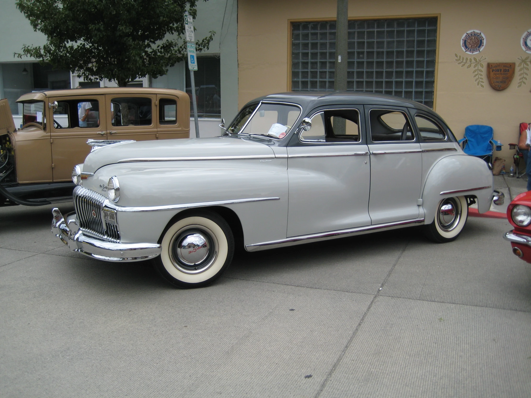 a grey vintage car on a street next to other old cars