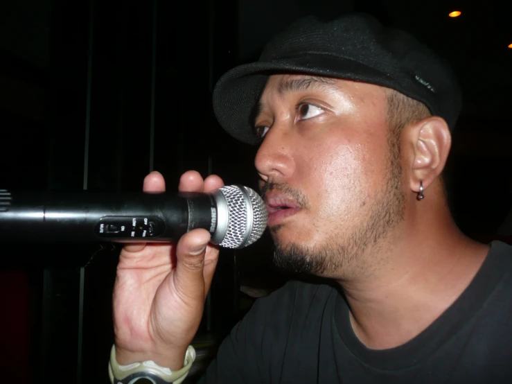 a man in a black hat is singing into a microphone