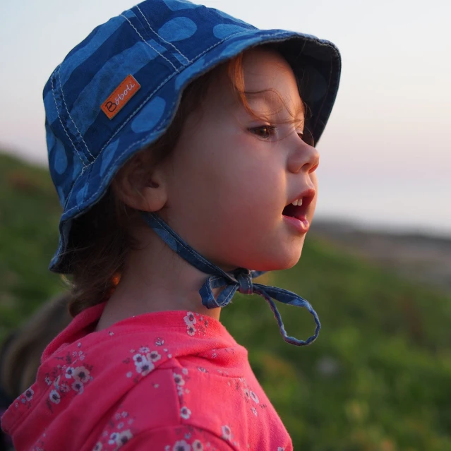 a little girl with a surprised look wearing a blue hat