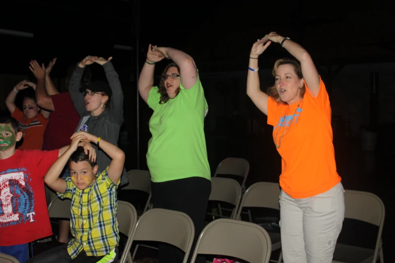 several adults and children standing up with arms extended in front of them