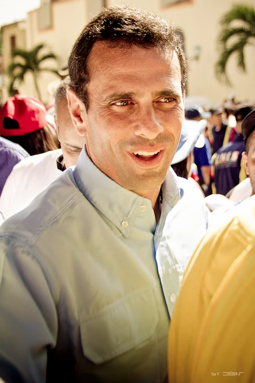 a man smiling at an event in the sun