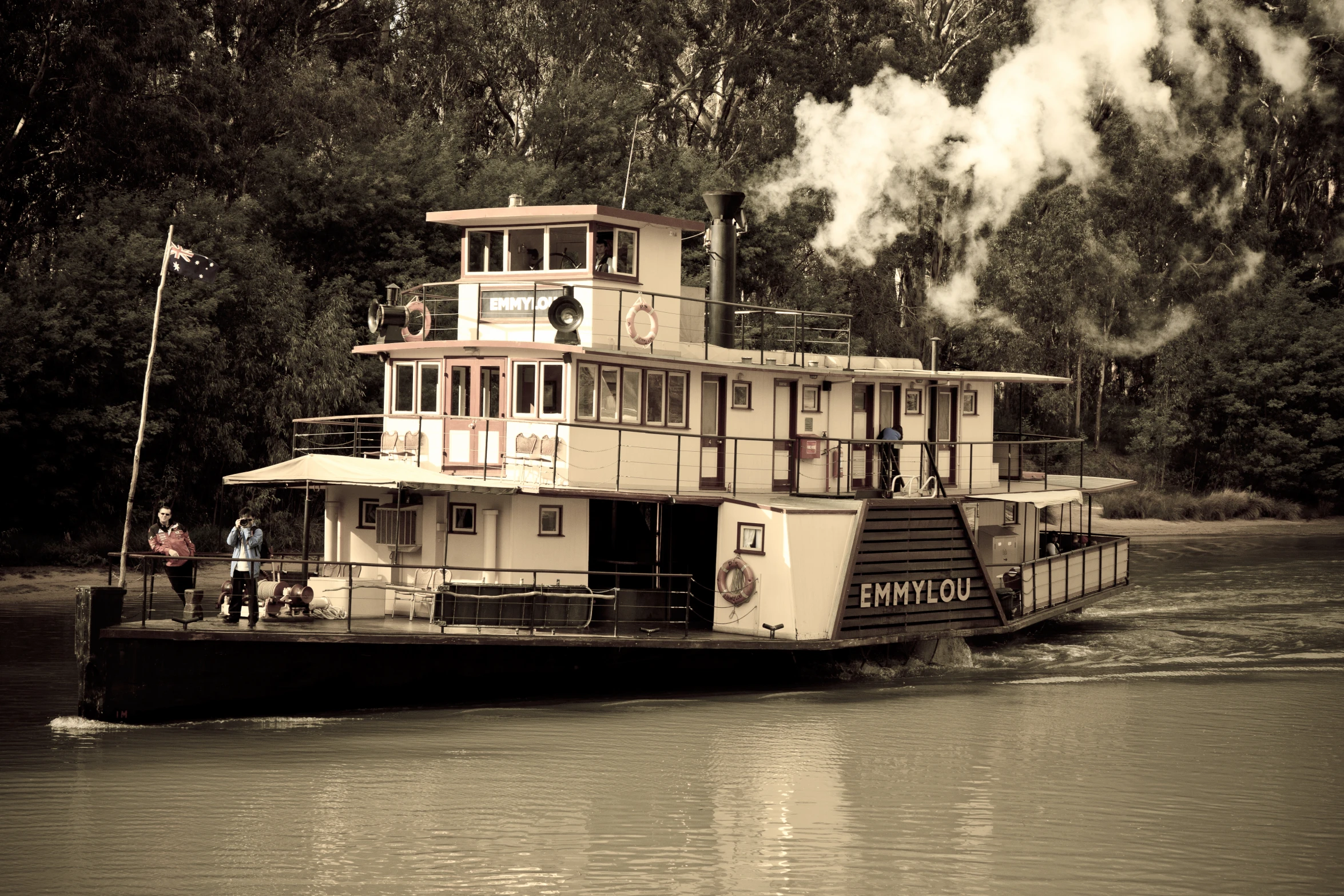 a boat floating down the river on a lake surrounded by trees