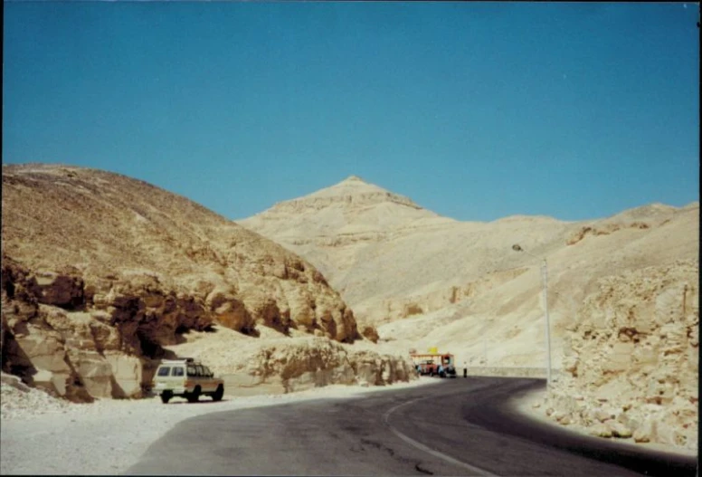 cars and trucks drive down the side of a mountainous road