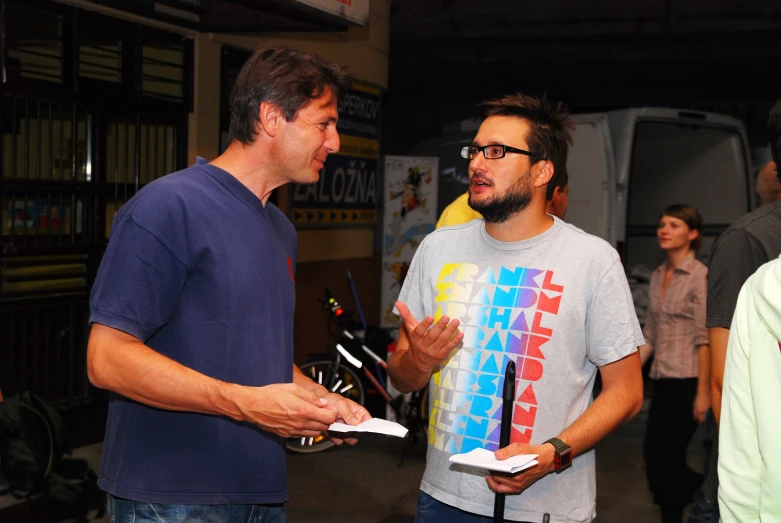 two men in a group talking together with books