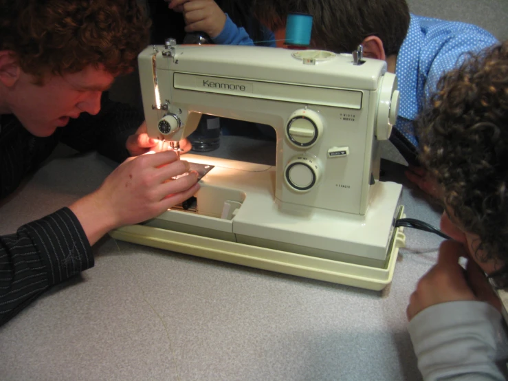 three people are looking at a sewing machine