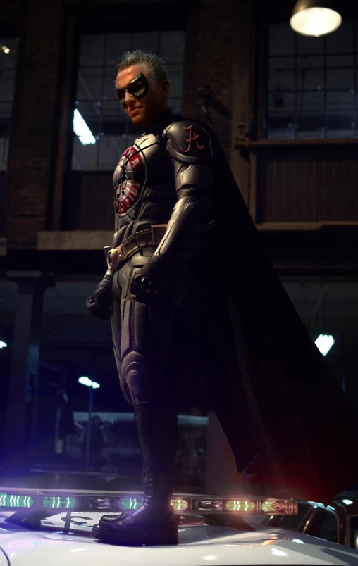 a man in a suit and mask on top of a car