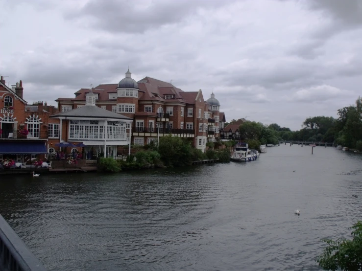 a wide canal with boats traveling in front of some brown buildings