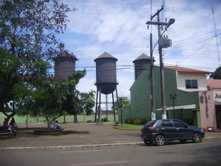 two water towers are near a car on a street
