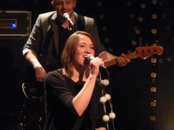 a woman holding a guitar and singing on stage