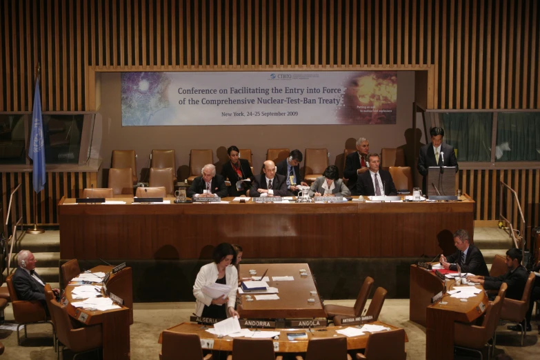 many people sit at long wooden tables, surrounded by chairs