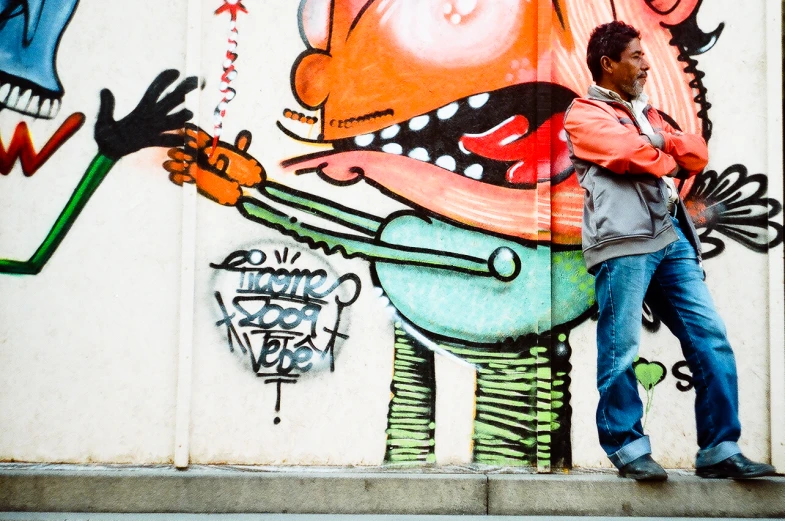 a man leans against a wall that has graffiti on it