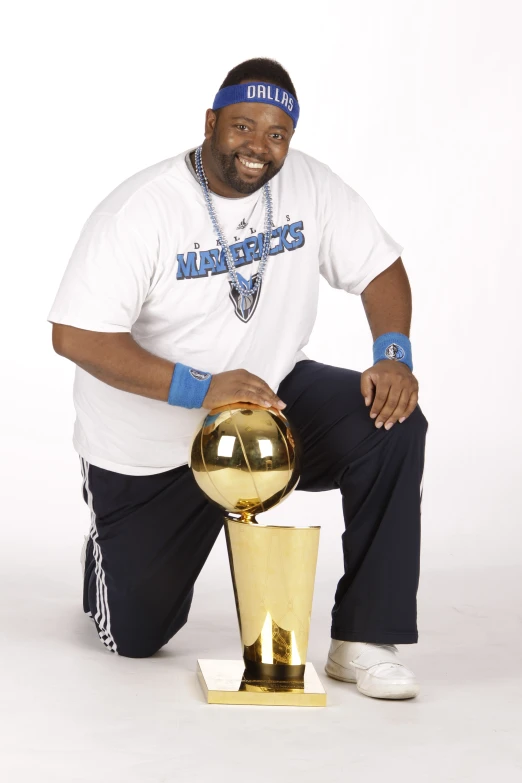 a man sits with his leg over a gold trophy