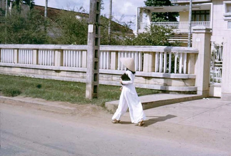 the  walks down the street in front of a fence