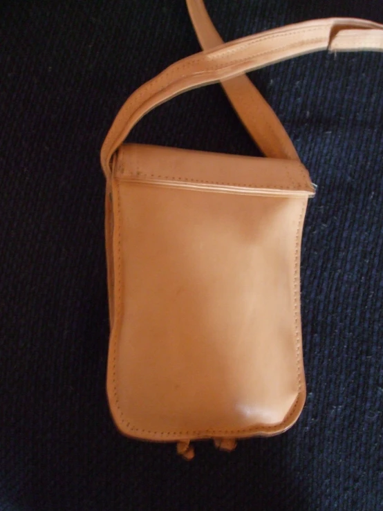 a tan leather purse hanging on the back of a backpack