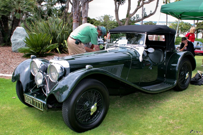 a classic car on display with men tending to it