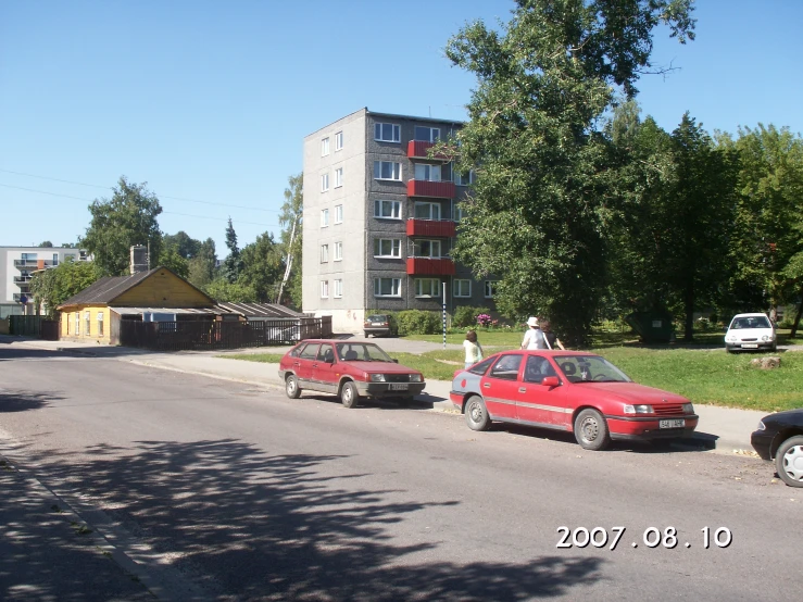 a couple of cars parked along the street with some people