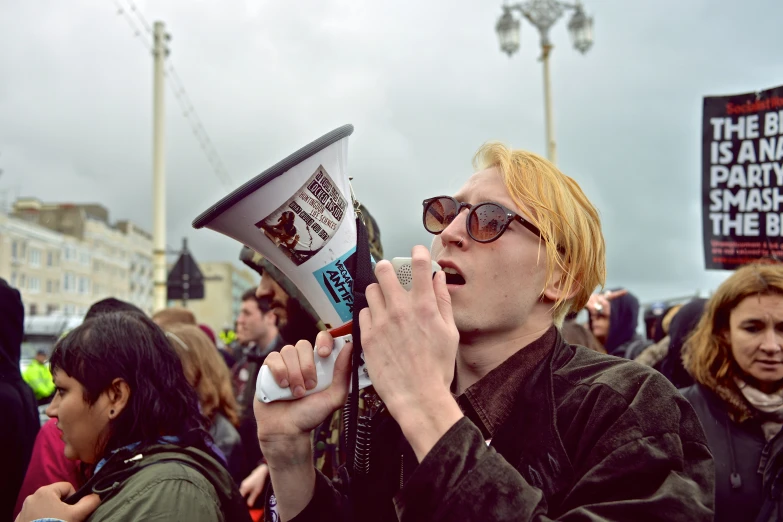 a man blows a megaphone while people hold signs