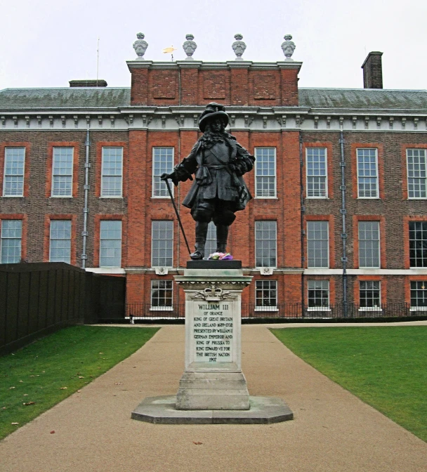 a statue of a man standing in front of an old brick building